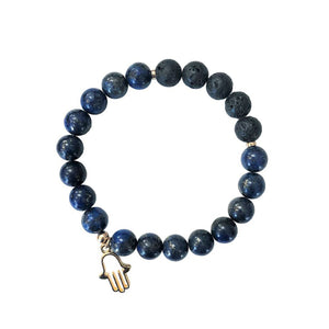 An aromatherapy bracelet made from blue lapis stones and black lava beads with a gold hamsa charm