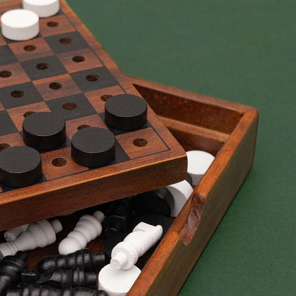 A checkmate travel set with playing pieces inside and on top of the box