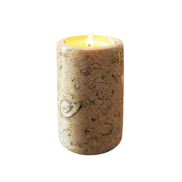 A fossil stone tea light candle holder, with a lit candle inside