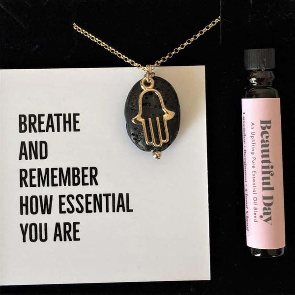A gift box showing the hamsa diffuser necklace and a bottle of essential oil