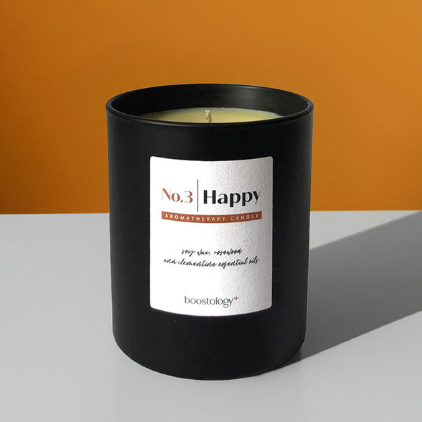 Black aromatherapy candle on a grey shelf with an orange wall