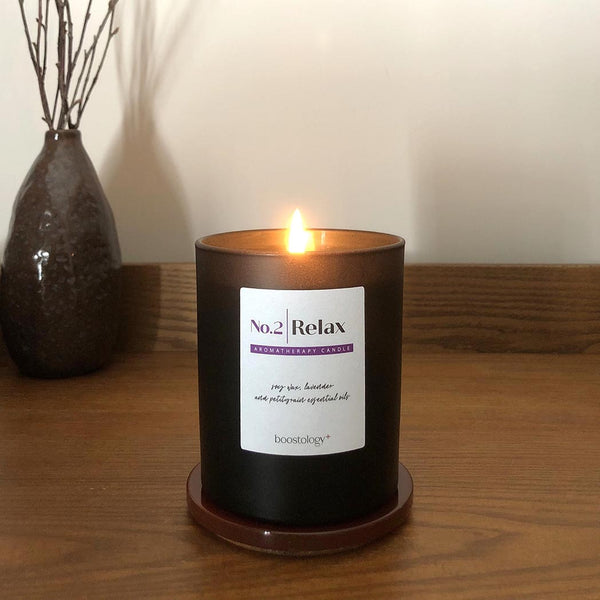 A lit soy wax candle on a wooden bedside table