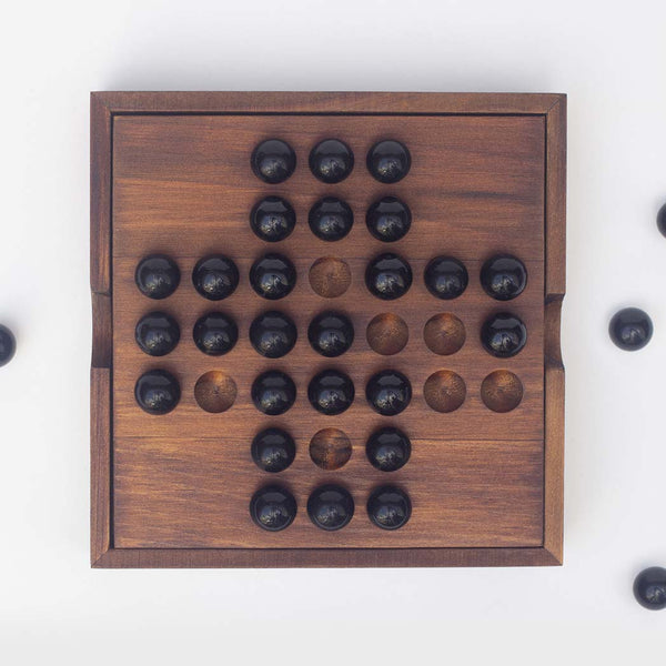 Black glass marbles sitting on top of the Solitaire game